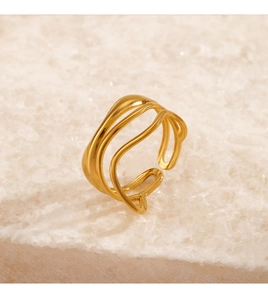 Detailed macro shot of a gold triple-layer wavy ring on a white textured mineral stone