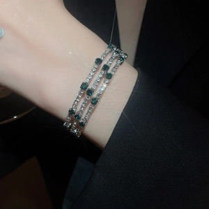 Detailed view of triple-layered silver bracelet with white zircons and emerald stones