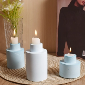 Ensemble de trois bougeoirs cylindriques étagés avec finition mate sur tapis tressé