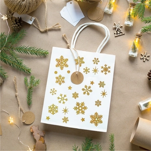 Detail of white Christmas gift bag with gold glitter snowflakes and pine decoration