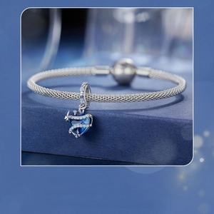 Dettaglio bracciale a maglia serpentina in argento con ciondolo a cuore blu brillante