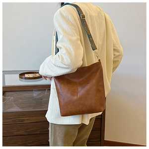Detailed shot of brown leather tote bag featuring ethnic embroidered wide shoulder strap