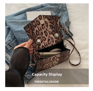 Detail shot showing the spacious interior of a leopard print crossbody bag with metal clasp