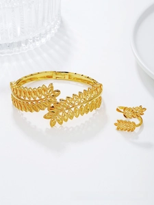 Detail of gold plated wheat leaf bracelet and ring set on an elegant white background