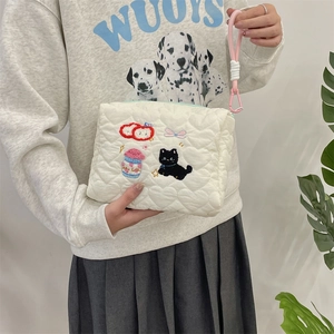 Detailed shot of cream quilted cosmetic bag with heart patterns and cat embroidery details
