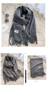 Close-up detail of dark grey cashmere-feel scarf with elegant fringes and brand label