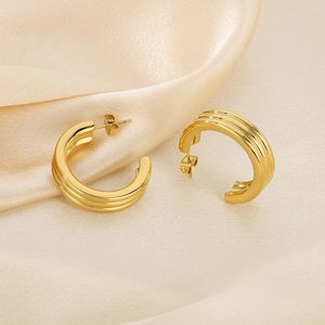 Golden C-shaped stainless steel earrings with triple wave texture on silk background