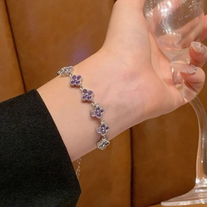 Detail showing shiny silver flower chain bracelet with six purple clover stones on a wrist