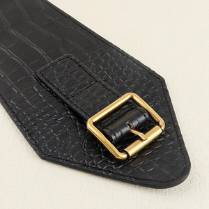 Macro detail of black crocodile embossed leather belt with a vintage gold pin buckle