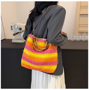 Detail of colorful woven straw tote with bamboo handles and leather strap in lifestyle setting