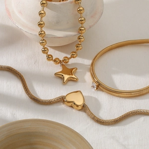 Gold star and heart pendant necklaces with a square zircon bracelet set on fabric