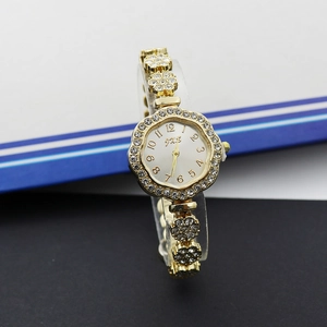 Gros plan d'une montre dorée pour femme en forme de pétale avec strass et cadran blanc