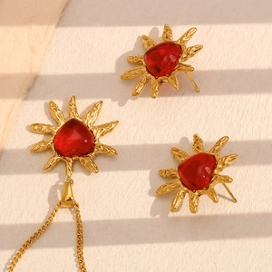 Detailed close-up of 18K gold sunburst jewelry set featuring red heart-shaped agate stones