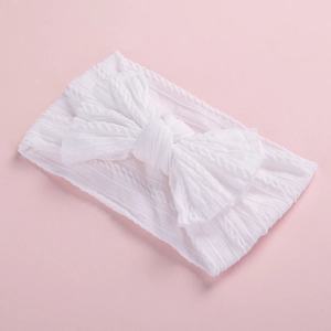 Close-up detail of a soft white jacquard nylon baby headband with a large decorative bow