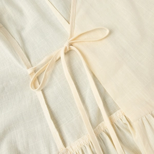 Détail macro d'une robe en coton avec des liens à la taille et une texture plissée chic
