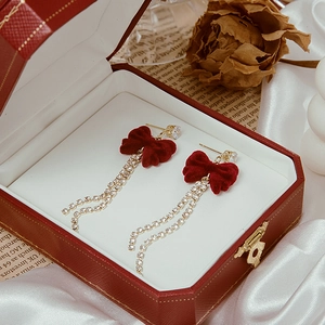 Detail of red velvet bow earrings with sparkling rhinestone tassels in a gift box