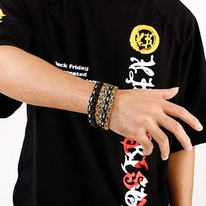 Close-up of gold, black and silver chunky stainless steel chain bracelets on a model wrist