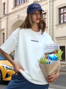 Dettaglio maglietta in cotone bianco con stampa ASSERTIVE e berretto Ritz PARIS ricamato