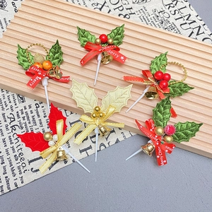 Christmas cake toppers set with holly leaves, bells and Merry Christmas ribbons on wood