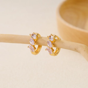 Elegant gold-plated huggie hoop earrings with three tiered lavender zircons on a wooden branch