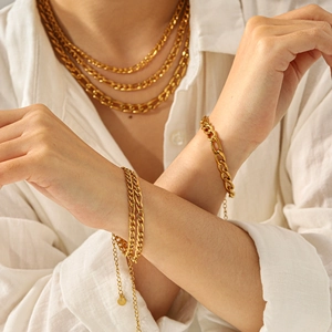 Polished 18K gold Figaro and curb chain necklace set layered with coin charm bracelets