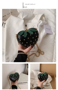 Close-up of black heart-shaped strawberry bag with gold rivets and leaf detail