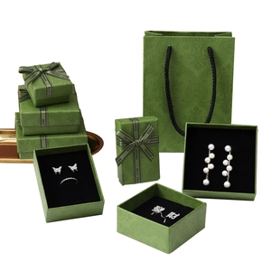 Elegant emerald green jewelry gift boxes with gold ribbons and matching carry bags