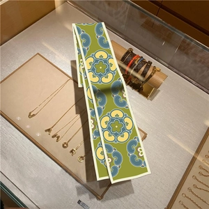 Detail of oil painting style green silk scarf with luxury jewelry on display stand
