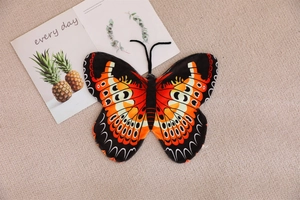 Flat lay of butterfly plush pillow skin with orange and black wing patterns on rug
