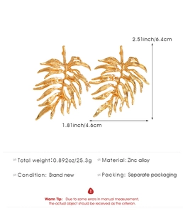 Detail view of large gold monstera leaf earrings with dimensions and material specs