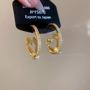 Macro shot of 18K gold plated C-shaped hoop earrings with F logo and pave zircons