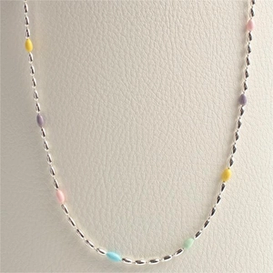 Sterling silver beaded necklace with colorful enamel rainbow olive charms on a cream stand