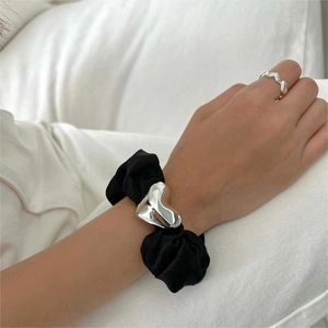 Detail of 925 sterling silver heart ring paired with a black satin heart hair scrunchie