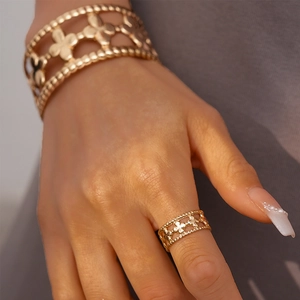 Detail of gold clover hollow bangle and ring set with beaded edges on a model