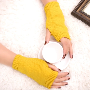 Detail of bright yellow knitted fingerless gloves on a soft white plush background