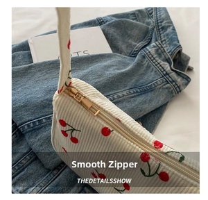 Detail showing white corduroy fabric with cherry embroidery and smooth golden zipper