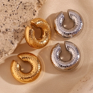 Detail of 18K gold and silver plated C-shaped earrings with hammered texture finish
