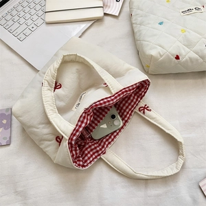 Detail of cream canvas tote bag with red bow embroidery and checkered red lining