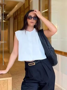 Chic women's white sleeveless shirt and black high-waist trousers with a woven shoulder bag