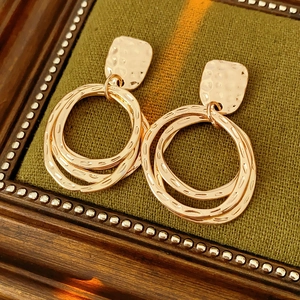 Detail of rose gold double hoop earrings featuring unique hammered metal textures
