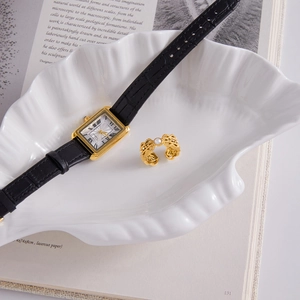Classic rectangle gold watch with black leather strap and pearl ring on white shell tray
