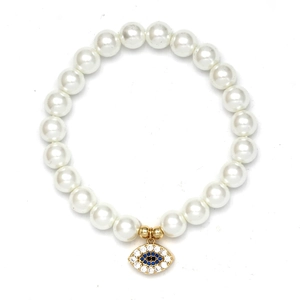 Detail eines Perlenarmbands mit Evil Eye Anhänger und weißen Kunstperlen in Gold