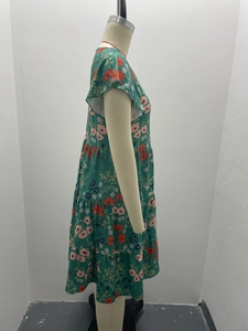 Detail showing the layered ruffle hem and vibrant floral pattern on a green summer dress