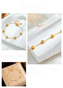 Detailed view of a gold heart pendant bracelet with a lobster clasp in a jewelry box