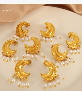 Makroaufnahme goldener Mondsichel-Ohrringe mit vier eleganten weißen hängenden Perlen