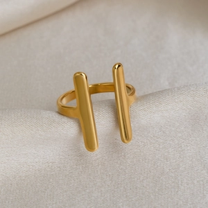 Macro shot of gold-plated double-bar ring on elegant champagne silk fabric background