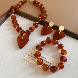 Detailed view of amber acrylic heart jewelry set with necklace bracelet and earrings