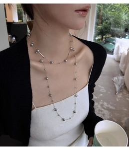 Detail of elegant silver layered beaded necklace featuring multiple metal ball chains on model