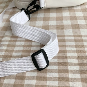 Détail de la bandoulière en nylon blanc avec boucle de réglage en plastique noir