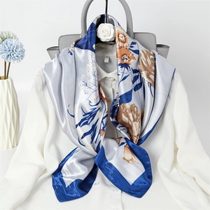 Close-up of elegant floral silk scarf with blue border styled on a white shirt
